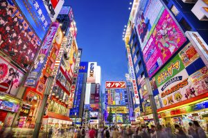 Tokyo, Japan - August 1, 2015: Crowds pass below colorful signs in Akihabara. The well known electronics district specializes in the sales of video games, anime, manga, and computer goods.