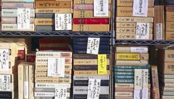 Second-hand books stacked and priced in window display of bookshop in Jimbocho, Tokyo.