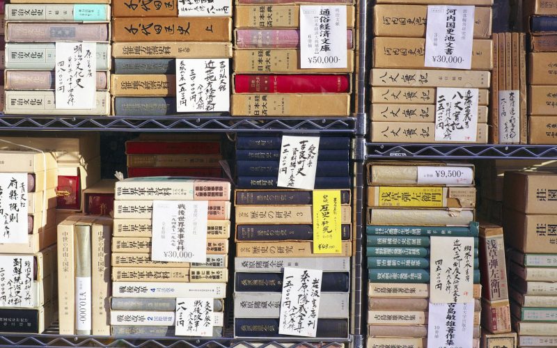 Second-hand books stacked and priced in window display of bookshop in Jimbocho, Tokyo.